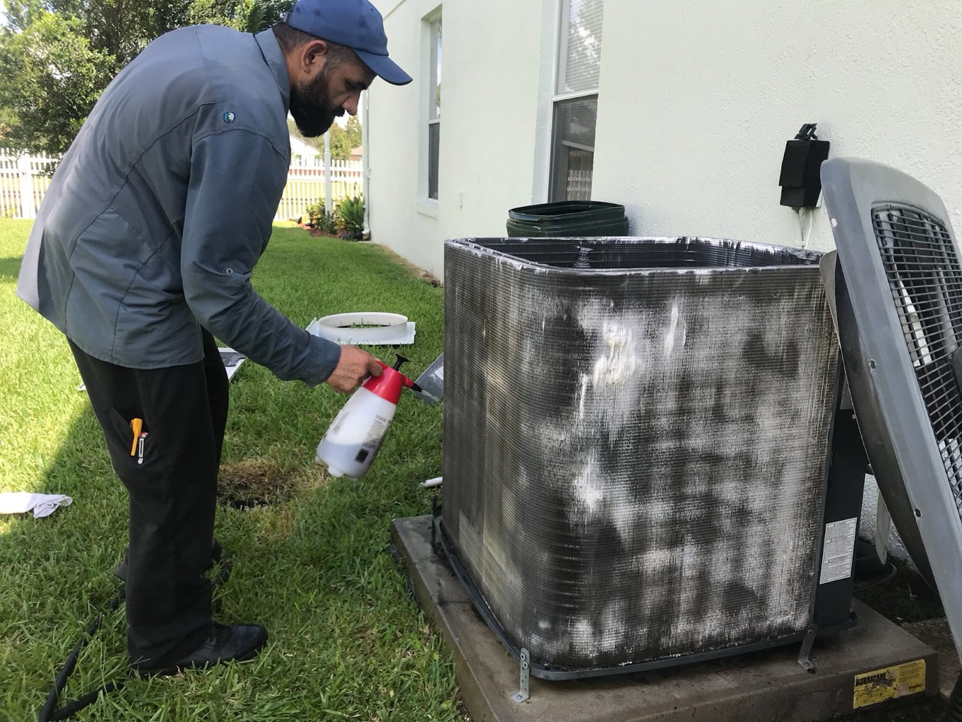 A Baburi technician foaming and cleaning outdoor AC coils on a service call in a St. Cloud yard