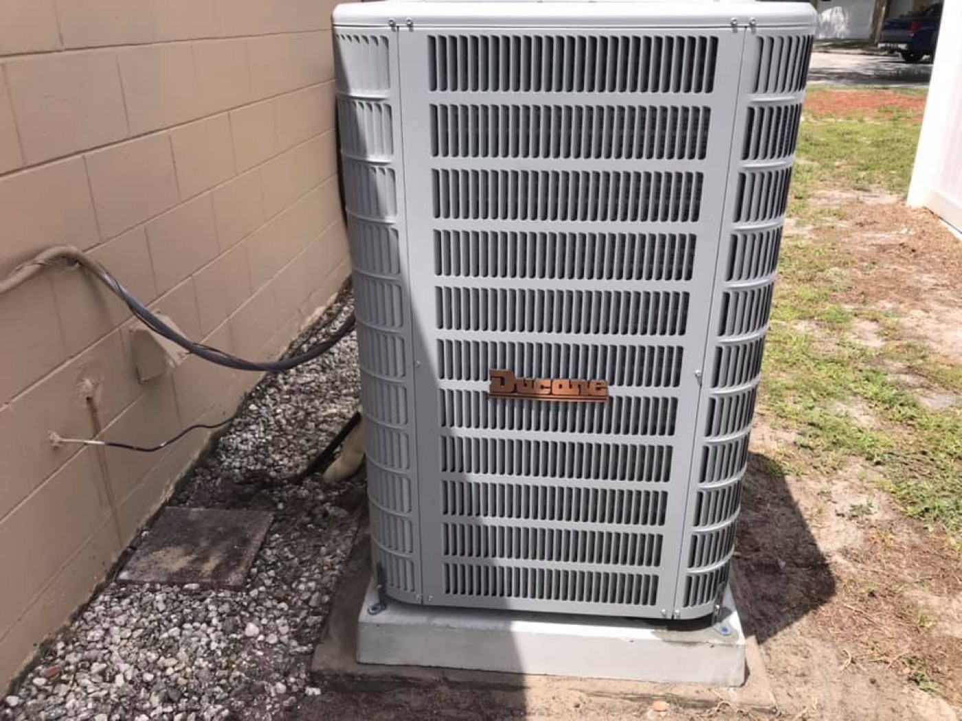New Ducane condenser installed on a concrete pad with refrigerant lines tied into the wall